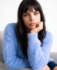 Woman wearing a woman's powder-blue angora cardigan sweater with pockets, showcasing soft, cozy fabric and elegant style